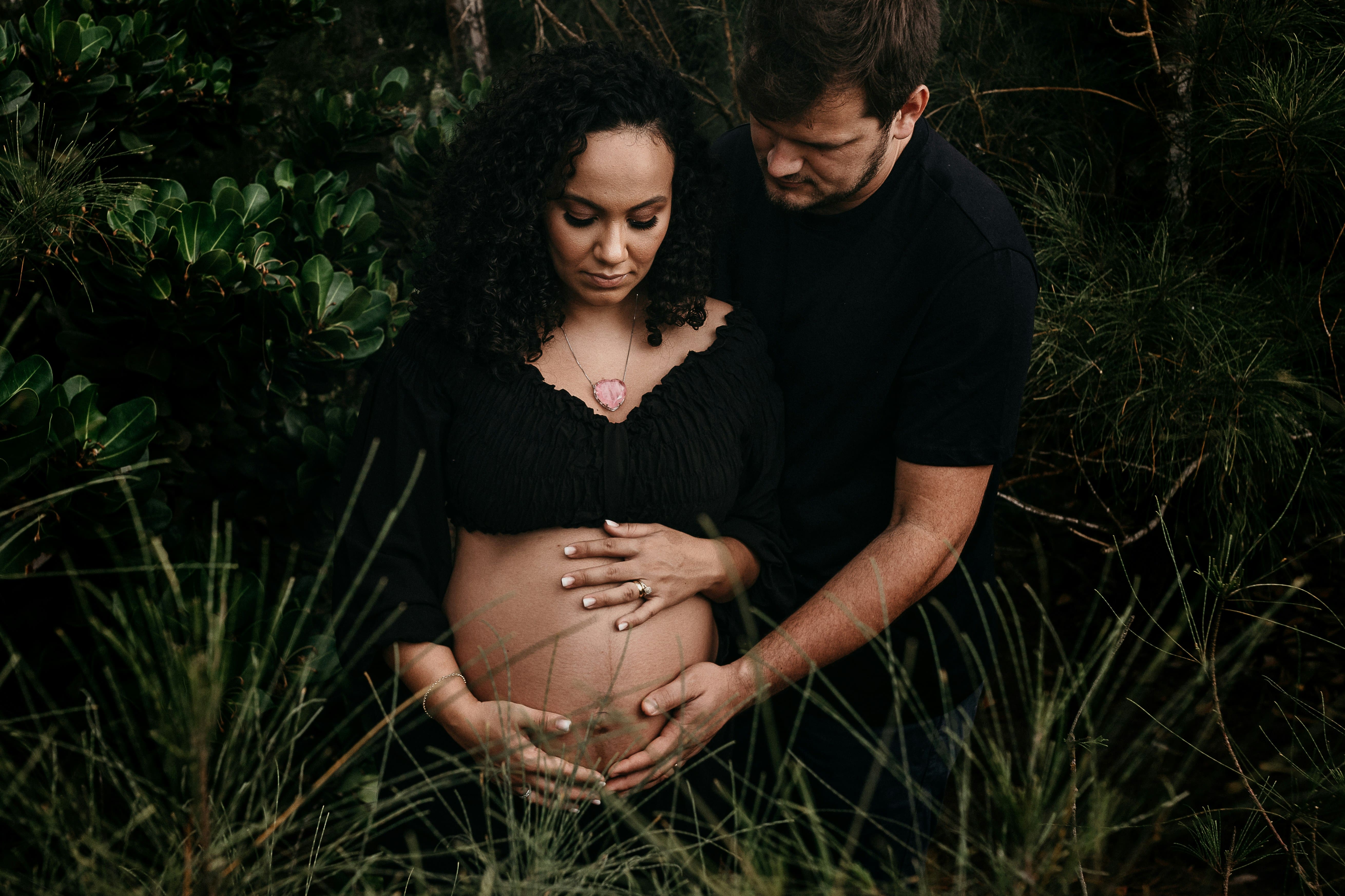Un couple hétéro dans la nature, la femme est enceinte et ils caressent tous les deux son ventre